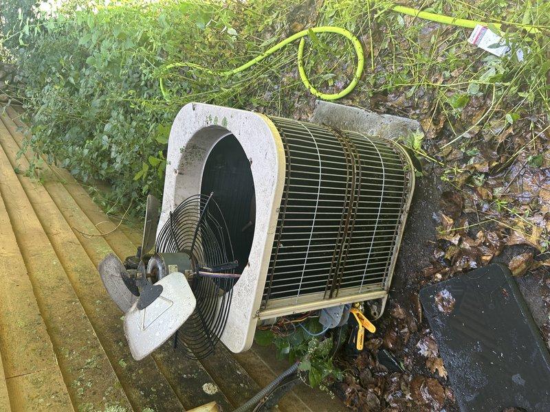 Responded to no cooling call on aging residential air conditioning system. Upon arrival, discovered water pooling beneath furnace due to completely plugged condensate drain line. Successfully cleared drain line, evacuating standing water from drain pan. Replaced heavily restricted air filter that was impeding airflow.

Proceeded to outdoor unit which was inoperative. Diagnosed failed dual run capacitor preventing compressor and condenser fan motor operation. Outdoor unit exhibited severe neglect with heavy dirt and debris accumulation on condenser coil restricting airflow. Fan housing showed significant physical damage to top panel, likely from hail impact, causing structural deformation.

Replaced failed capacitor and performed thorough coil cleaning to restore proper heat transfer. System restored to operational status with adequate cooling performance. However, noted condenser fan motor operating out of balance due to damaged housing, which will likely lead to premature motor failur