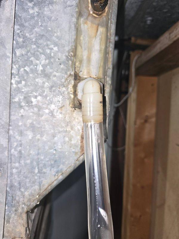 Responded to water leak complaint on Heil R22 air conditioning system. Upon inspection, replaced condensate tube and fitting, but leaking persisted. Further investigation revealed cracked evaporator coil and heavily rusted condensate pan allowing water to leak onto heat exchanger and into drain area. Observed extremely hot liquid line indicating potential refrigerant restriction, dirty outdoor coil, and missing condenser data plate preventing model confirmation. Air filter condition was acceptable. Due to extent of damage including compromised evaporator coil, failed condensate pan, and overall system age, recommended complete system replacement including evaporator coil and condenser unit. Documented conditions with photos showing corroded drainage components and rust staining at pipe connections.