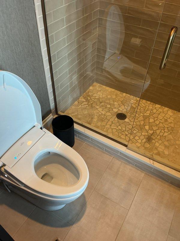 Responded to service call for sewer odors affecting multiple toilets throughout residential property. Conducted comprehensive inspection of six toilet fixtures, including units equipped with bidet seats. Investigated potential sources of sewer gas infiltration, examining wax ring seals, flange connections, and trap integrity. Performed thorough cleaning and testing procedures on all affected fixtures to identify and resolve odor issues. Documented conditions of bathroom facilities with detailed photography showing modern installations with contemporary tile work and fixtures.
