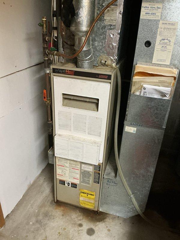 Responded to no cooling complaint on residential HVAC system. Upon arrival, found indoor evaporator coil freezing up and blocking airflow. System was critically low on obsolete refrigerant. During diagnostic testing, refrigerant lines and compressor froze up almost immediately. Reset power to system, but compressor failed to restart, indicating likely compressor failure due to extended operation with insufficient refrigerant charge. 

Inspected furnace and identified original equipment with manufacture date of 1992. Determined aged furnace is probable source of refrigerant leak and system inefficiency. Given the age of equipment (30+ years), obsolete refrigerant type, failed compressor, and compromised system integrity, recommended complete system replacement rather than repair.

Scheduled same-day estimate for new furnace and air conditioning system replacement. Documented existing equipment configuration and conditions with photographs showing indoor furnace/air handler installation 