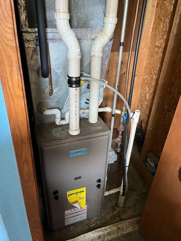 Responded to no cooling complaint on 10+ year old AC system with reported rattling noise from blower assembly. Upon inspection, discovered a picture lodged in the blower wheel causing the noise. Removed foreign object and restored normal blower operation. Identified secondary issue with condensate leaking back through intake, dripping onto gas valve and electrical components in upper furnace cabinet. Installed in-line drain on furnace intake to resolve drainage issue. Replaced existing thermostat with customer-supplied unit. Tested complete system operation including cooling cycle, airflow, and thermostat functionality. All components operating properly with no noise or leakage present at completion.
