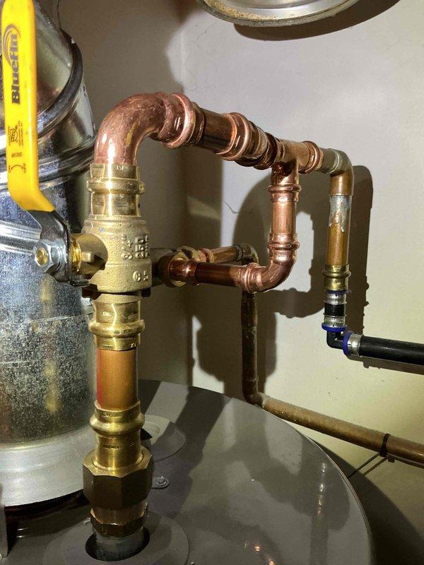 Responded to service call and installed thermostatic mixing valve on residential water heater system. Shut off water supply, cut into hot and cold water lines directly above the water heater unit, and integrated new brass mixing valve with proper copper pipe connections and fittings. Adjusted water heater temperature settings to optimal level, pressure-tested all connections for leaks, and verified proper system operation with correct water temperature delivery at fixtures. All work completed with one-year workmanship warranty.