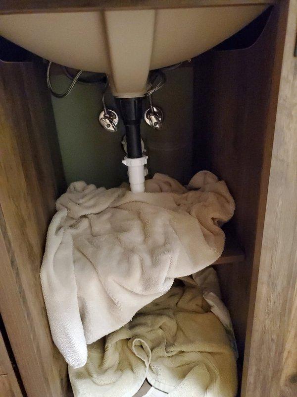 Responded to emergency water leak under bathroom vanity with water pooling and main shut-off valve inoperative. Diagnosed failed angle stop under sink and defective main water shut-off valve. Replaced main shut-off valve to restore water control to property and installed new angle stop under bathroom sink, resolving all active leaks.