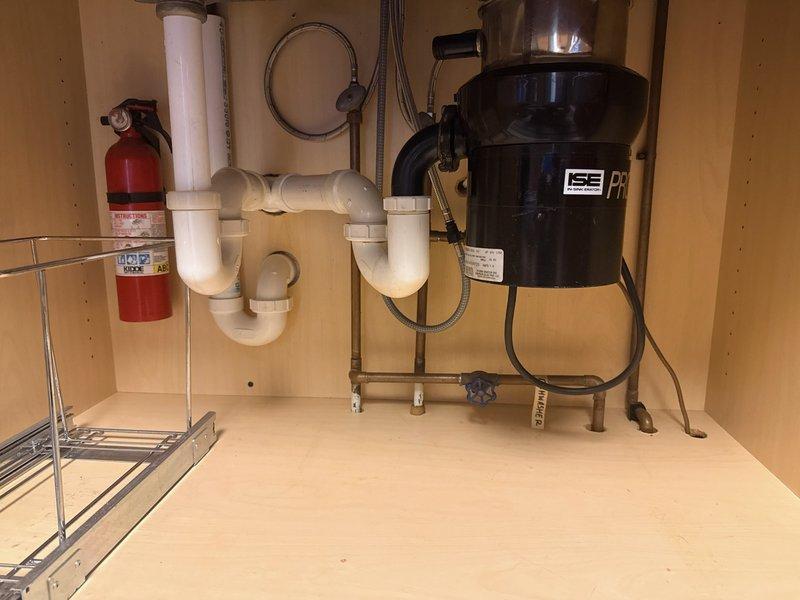Completed kitchen sink conversion from dual-basin to single-basin configuration. Reconnected kitchen drain plumbing using PVC P-trap assembly, ensuring proper alignment and secure connections to vertical drain lines. Verified garbage disposal unit connections, water supply lines, and tested system for proper drainage and leak-free operation.