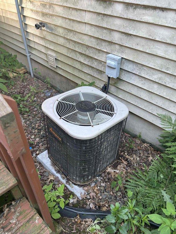 Responded to no cooling complaint on 26-year-old central air conditioning system running but unable to maintain temperature. Upon arrival, found evaporator coil frozen solid. Allowed coil to thaw sufficiently to perform diagnostics. Verified adequate airflow across coil once thawed. Performed refrigerant charge check and confirmed system was significantly low on R-22 refrigerant. Inspected outdoor condenser unit and refrigerant lines, noting severe corrosion and rust deterioration on copper piping connections and mounting hardware, indicating age-related degradation and potential leak points. System showing multiple signs of end-of-life failure including refrigerant loss, corroded components, and diminished cooling capacity. Given the age of the equipment, obsolete R-22 refrigerant requirements, extent of corrosion damage, and cost of repairs versus replacement, provided customer with comprehensive pricing options for both refrigerant recharge repair and complete system replacement. Co