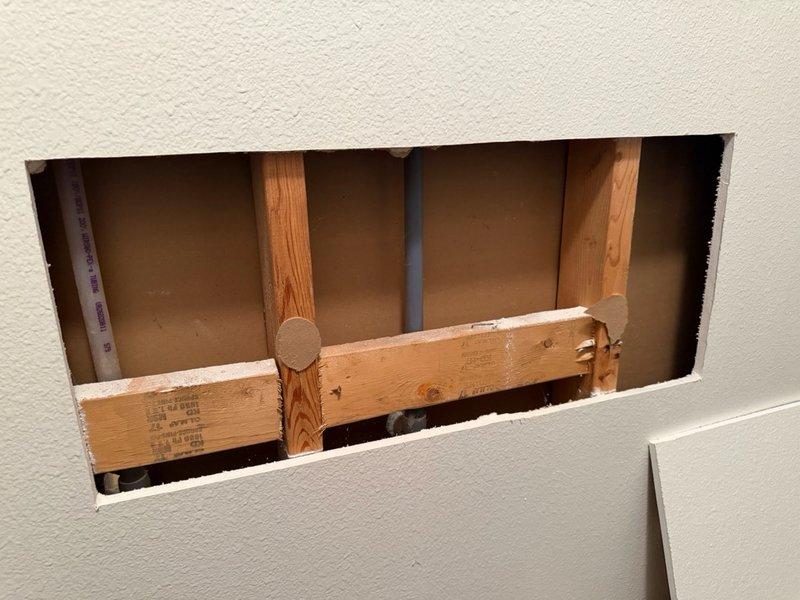 Responded to emergency call for mystery water leak in closet with saturated carpet on slab foundation. Upon arrival, opened access panel in drywall to inspect for plumbing leaks in wall cavity. Thoroughly examined exposed studs, framing, and all visible plumbing lines within the wall structure. Found no evidence of active water leaks, burst pipes, or moisture in the wall cavity—all components were completely dry. Based on findings and timeline correlation with recent roof replacement completed three weeks prior, determined leak source was not plumbing-related. Recommended homeowner contact roofing contractor to inspect roof penetrations and vent stack flashing for potential water intrusion. Advised engaging water restoration specialist to extract moisture from carpet, assess extent of water damage, and inspect slab foundation for potential foundation leaks or groundwater issues. Documented conditions with photographs showing access opening and affected areas.