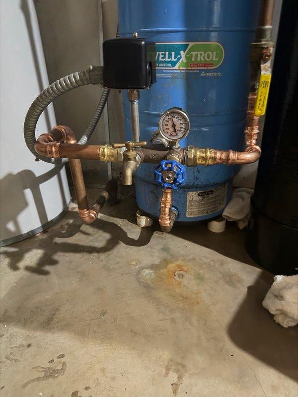 Responded to a leak at the pressure tank assembly caused by a pinhole leak on the elbow joint connected to the tank. Upon inspection, identified the compromised copper bend and deteriorated tank tee fitting as the source of the water loss. Replaced the defective tank tee with a new brass fitting and repaired the affected section of copper piping using proper soldering techniques. Tested the pressure tank system for leaks and verified proper operation of all valves and connections. System restored to full functionality with no active leaks detected.