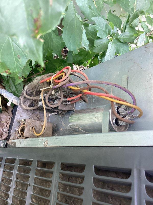 Responded to no-cooling call at duplex property. Upon inspection, found 15-year-old central air conditioning system completely non-operational. Outdoor condensing unit exhibited severe neglect with heavily corroded electrical connections, deteriorated wiring, and substantial accumulation of dirt and debris throughout the unit. 

Diagnostic testing revealed failed run capacitor preventing compressor and condenser fan operation. Electrical terminal housing showed extensive oxidation and weather damage from prolonged exposure to elements. Multiple wire connections displayed corrosion requiring attention during capacitor replacement.

Replaced defective capacitor with properly rated component. Performed thorough cleaning of condensing unit, removing accumulated dirt, debris, and vegetation matter from coils and electrical compartment. Cleaned and secured all electrical connections in terminal area. Cleared surrounding vegetation encroaching on unit for proper airflow.

System tested succes