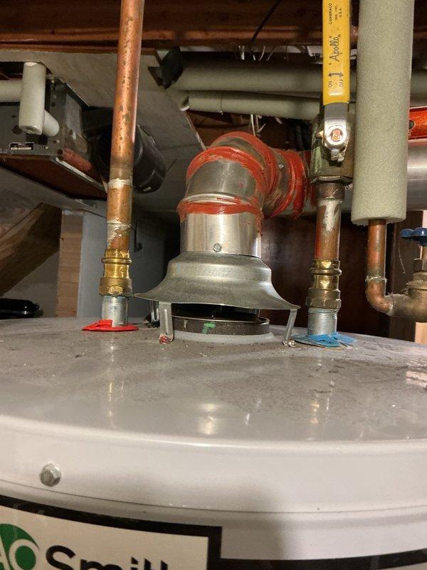 Responded to service call for melting observed on top of 50-gallon natural gas chimney vent water heater. Upon inspection, discovered improper chimney venting installation identified during home inspection. Measured chimney vent and found back pitch of approximately 1 inch over 1-foot span, preventing proper draft. Observed heat damage and melting on trim rings at water heater nipple connections due to inadequate venting. Additionally found flue damper cocked approximately quarter turn out of proper position, further restricting exhaust flow.

Disassembled existing chimney vent system and shortened vertical portion to correct improper pitch. Reinstalled chimney vent piping with proper upward pitch to ensure adequate draft. Adjusted and repositioned flue damper to correct alignment. Fired water heater and verified proper draft by confirming heat rising through vertical chimney portion. Confirmed all exhaust gases venting appropriately with no heat buildup at trim rings or top of unit. S