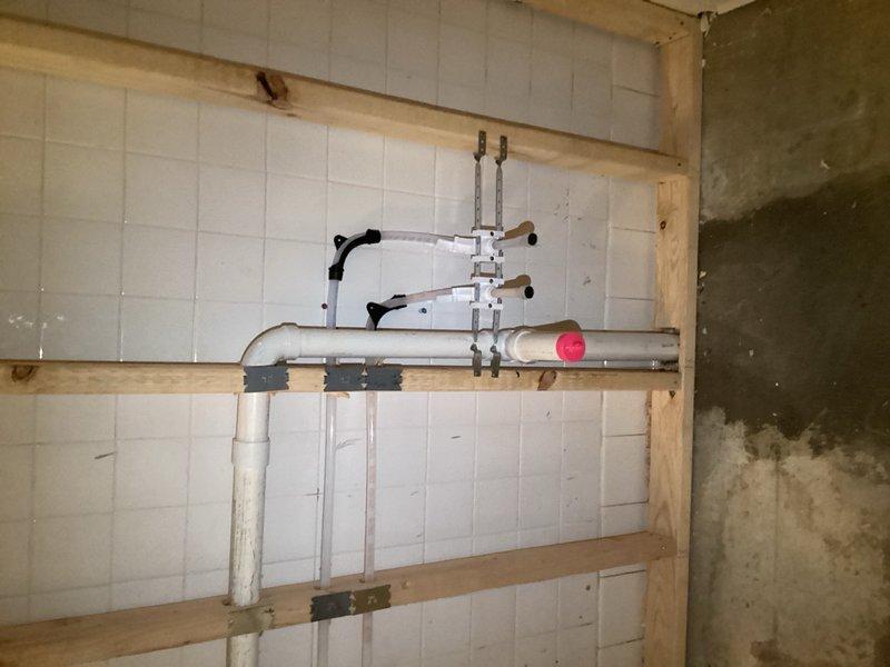 Completed water line rough-in installation for shower valve with PVC piping and mounting brackets secured to wall framing. Installed well pump control box and rewired pressure switch connections, verifying electrical power supply to system. Upon testing, pump failed to operate despite confirmed power delivery; recommended specialist well service contractor for pump diagnostics and repair to resolve operational issue.
