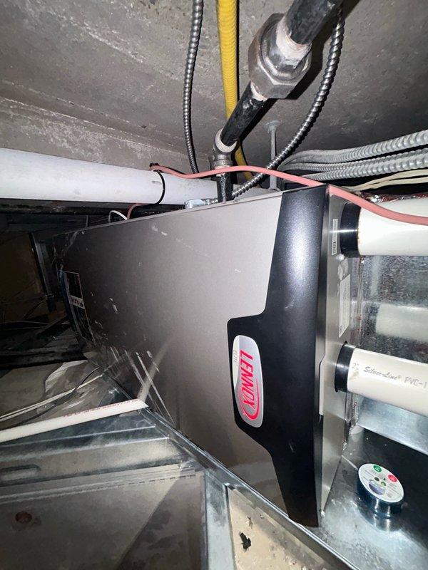 Responded to a service call for a Lennox air conditioning system experiencing water leakage while maintaining cooling capacity. Upon inspection, diagnosed a clogged condensate drain line as the primary issue. Utilized wet vacuum to extract accumulated condensation water from the drain pan and line, then cleared the blockage using compressed CO2. Thoroughly inspected evaporator coils and drain pan, confirming no damage or additional leaks present. Performed comprehensive cleaning of both interior and exterior sections of the condensate drain line using vacuum extraction methods. Flushed drain system with 2-3 gallons of water to verify proper flow and confirmed audible drainage through wall cavity, indicating complete line clearance. System tested and verified to be cooling normally with condensate draining properly through cleared line. Unit restored to full operational status.