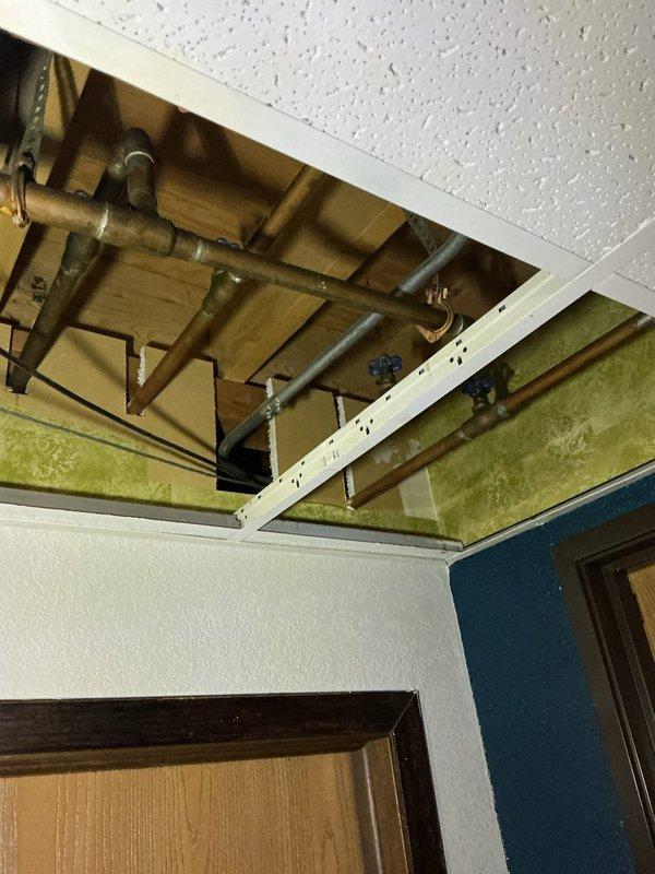 Completed rough-in of supply line and drain connections through ceiling cavity for commercial ice maker installation. Installed Avantco commercial ice maker unit in corner location, connecting water supply and drain lines per specifications, with unit mounted on casters for mobility and positioned for convenient access to ice dispensing panel.