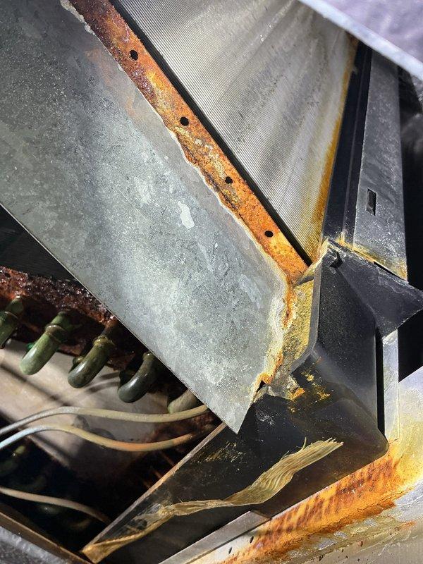 Performed air conditioning tune-up on 22-year-old residential system. Found clogged evaporator drain pan and capacitor reading out of specification. Replaced failed capacitor and removed debris from drain pan to restore proper drainage. Observed significant corrosion and rust on evaporator coil and metal housing components, indicating advanced equipment deterioration. Recommended system replacement due to age and extent of corrosion compromising unit integrity and efficiency.