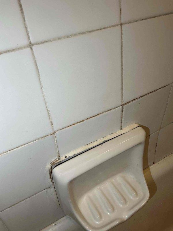 Responded to water leak causing basement flooding from upstairs bathroom. Identified source as failed caulking and grout deterioration around bathtub tile joints and soap dish fixture. Removed old caulking, cleaned and prepared surfaces, and re-caulked all tile joints to create proper water barrier and prevent further water intrusion into basement below.