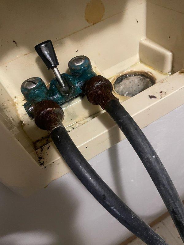 Responded to a water leak issue involving malfunctioning washing machine shut-off valves that failed to completely stop water flow. Removed the deteriorated dual shut-off valve assembly showing significant rust and corrosion on threaded connections. Installed new brass dual-handle shut-off valve with proper sealing, restored water supply, and verified all connections were secure with no leaks present upon completion.