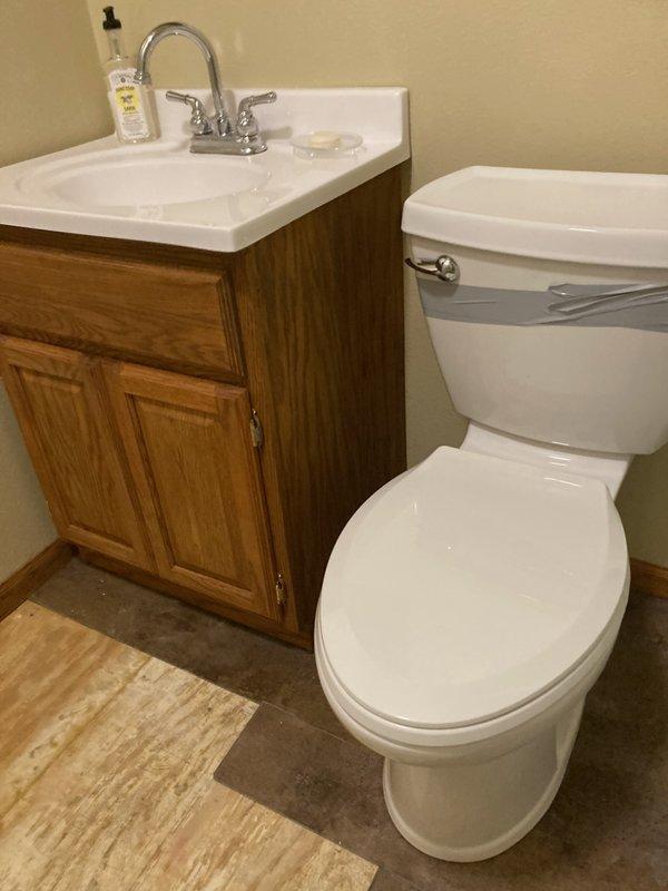 Responded to emergency plumbing call where a cracked toilet was discovered actively leaking and saturating the bathroom floor. Removed damaged two-piece toilet and disconnected water supply line at shut-off valve. Removed bathroom vanity with integrated sink and faucet assembly to allow access for flooring restoration. Coordinated with restoration company for water damage assessment and floor repairs. Fixtures removed and stored for disposal, with bathroom prepared for flooring contractor to complete repairs before new fixture installation can proceed.