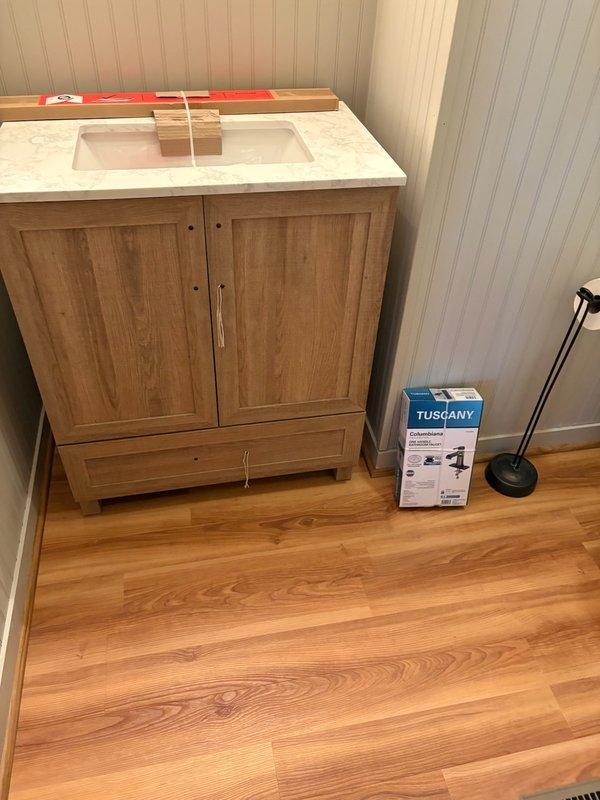 Completed installation of customer-supplied bathroom vanity with integrated sink basin and chrome faucet fixture. Connected all water supply lines to existing shut-off valves and verified proper drainage and leak-free operation of all plumbing connections.