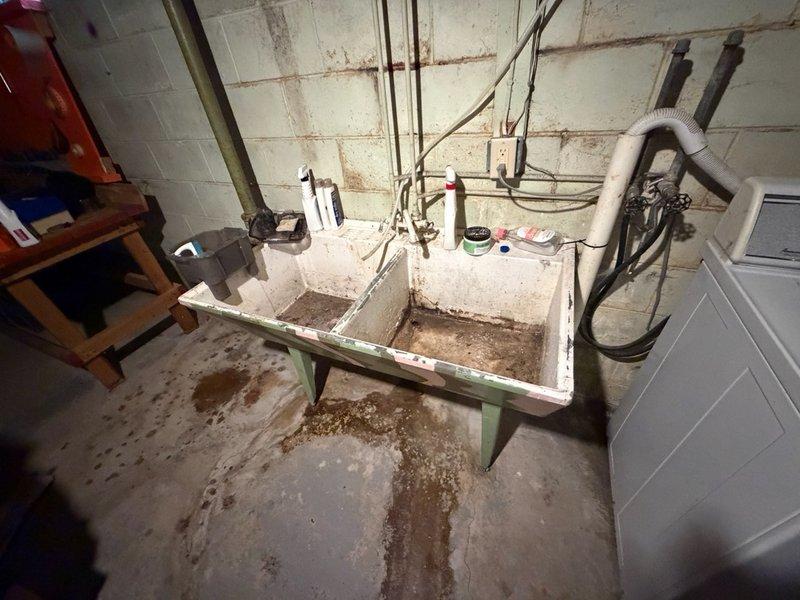 Responded to clogged laundry tub in basement utility area. The double-basin sink was backed up due to accumulated washing machine debris and lint buildup in the drain line. Deployed air snake to clear the obstruction, successfully restoring proper drainage. Ran water through both basins for five minutes to verify complete clearance and confirm system was draining at normal flow rate without backup.