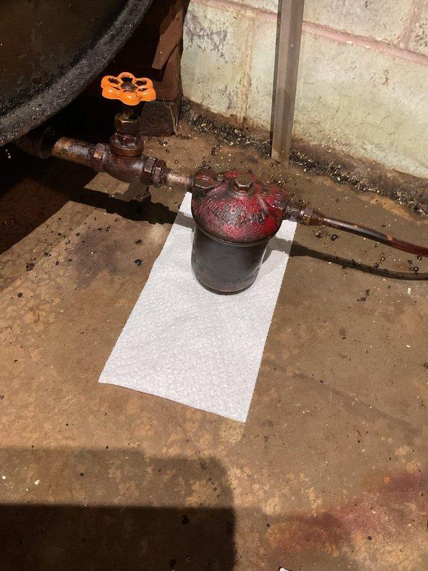 Responded to no cooling complaint and furnace fan continuously running. Diagnosed and replaced faulty thermostat, restoring proper system operation and resolving continuous fan issue. Investigated reported oil leak at filter location following previous maintenance visit. Inspected oil filter assembly and cleaned surrounding areas. Filter and gasket appeared secure with no active leaking observed. Identified loose fitting at bottom of oil tank as potential leak source. Advised customer that tank fitting requires attention from fuel company as it falls outside HVAC scope of work. Verified system cycling properly with new thermostat installed. All HVAC components functioning as designed upon completion.