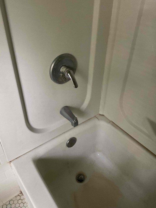 Responded to customer callback regarding dissatisfaction with recently installed tub and shower faucet handle. Upon arrival, customer expressed concerns about the functionality and appearance of the replacement handle assembly. Conducted visual inspection of the chrome single-handle control valve and tub spout system mounted on the bathtub enclosure. Documented existing conditions with photographs showing the white alcove-style tub installation, wall-mounted faucet assembly, and surrounding bathroom fixtures. Noted visible water staining and discoloration along caulk lines and wall panel seams, which appeared to be pre-existing conditions unrelated to recent work. Discussed customer's specific concerns regarding handle operation and performance compared to previous fixture. No additional diagnostic work or repairs performed during this visit.