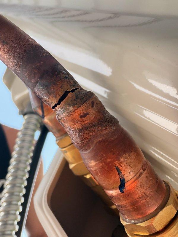 Responded to no-cooling complaint on DIY-installed Mr. Cool mini-split heat pump system less than one year old. Upon inspection, discovered visible crack in pre-vacuumed copper line set causing refrigerant leak, with extensive corrosion and oxidation present on the damaged section. Documented damage with photos showing compromised line set integrity and scheduled follow-up appointment with advisor to discuss line set replacement and system recharge options.