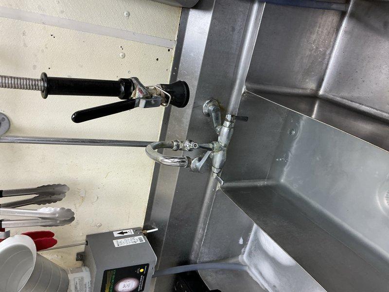 Responded to a clogged drain at a commercial deli location. Successfully cleared a blockage located approximately 10 feet into the pan wash sink drain line using appropriate drain cleaning equipment. During the service visit, documented additional plumbing issues requiring future attention, including a faucet and compression fitting that need replacement, a leaking three-compartment sink, and a hand wash sink with slow drainage caused by improper back-pitched piping within the wall. Photographed all identified issues for parts ordering and future repair scheduling.