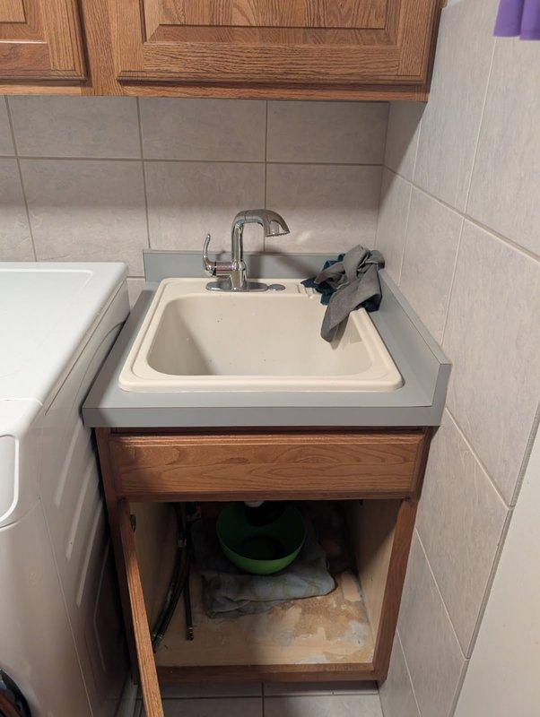 Responded to an active water leak beneath the laundry room sink. Upon inspection, identified a corroded strainer basket as the source of the leak. Attempted to tighten the existing strainer basket, but the leak persisted due to deterioration of the component. Removed and replaced the corroded strainer basket with a new unit. Following installation, performed leak testing by filling the sink basin and draining it three times to verify proper seal and confirm no water discharge from the drain assembly. All connections remained dry with no signs of leakage. Cleaned work area and restored utility room to normal operating condition.