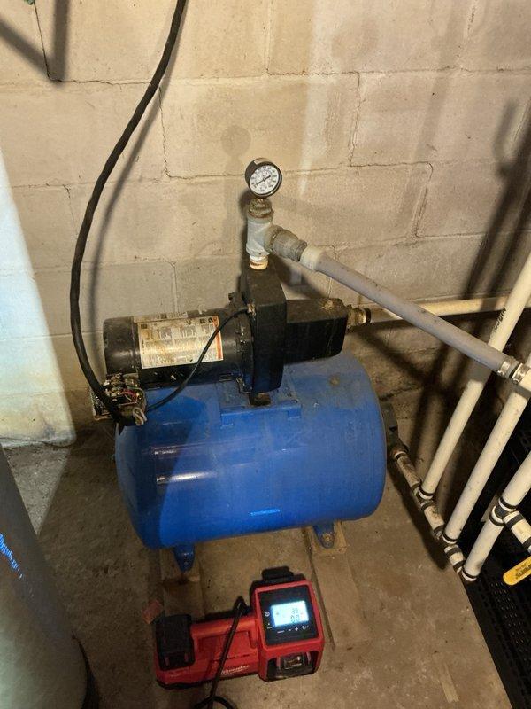 Responded to no water pressure complaint on shallow well jet pump system. Upon arrival, performed diagnostic testing on blue horizontal pressure tank assembly and pump motor. Verified pressure switch operation was within normal parameters and confirmed pump remained primed with no loss of suction. Inspected and tested check valve functionality - found to be operating correctly. Conducted systematic troubleshooting to isolate cause of water supply failure. Diagnostic meter readings and visual inspection indicated pump motor failure as primary issue. Determined well running dry as secondary possibility but assessed as unlikely based on system conditions. Documented equipment configuration including pressure tank, pump assembly, gauge readings, and piping connections with photographic evidence. Recommended pump replacement to restore water pressure and system functionality.