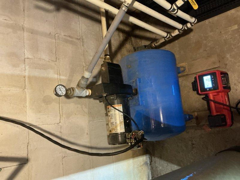 Responded to no water pressure complaint on shallow well jet pump system. Upon arrival, performed diagnostic testing on blue horizontal pressure tank assembly and pump motor. Verified pressure switch operation was within normal parameters and confirmed pump remained primed with no loss of suction. Inspected and tested check valve functionality - found to be operating correctly. Conducted systematic troubleshooting to isolate cause of water supply failure. Diagnostic meter readings and visual inspection indicated pump motor failure as primary issue. Determined well running dry as secondary possibility but assessed as unlikely based on system conditions. Documented equipment configuration including pressure tank, pump assembly, gauge readings, and piping connections with photographic evidence. Recommended pump replacement to restore water pressure and system functionality.