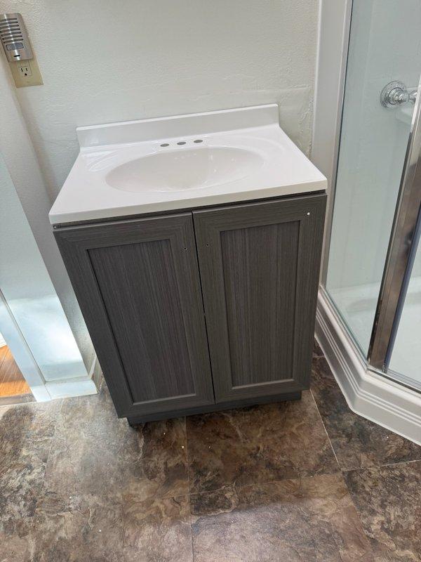 Installed new Moen Chateau faucet on recently installed bathroom vanity with white integrated sink basin. Connected water supply lines to faucet assembly through pre-drilled mounting holes and completed all plumbing connections to ensure proper water flow and drainage functionality.
