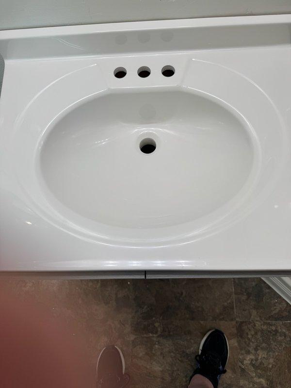 Installed new Moen Chateau faucet on recently installed bathroom vanity with white integrated sink basin. Connected water supply lines to faucet assembly through pre-drilled mounting holes and completed all plumbing connections to ensure proper water flow and drainage functionality.