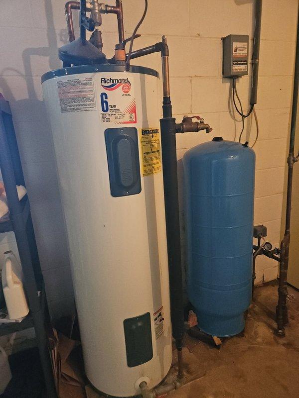 Responded to no hot water complaint and diagnosed electric water heater failure due to excessive sediment and calcium buildup in tank bottom. Removed existing non-functional unit and installed new Richmond brand electric water heater with 6-year warranty. Connected all copper supply lines, electrical wiring to panel box, and verified proper integration with existing blue pressure tank and water treatment system. Tested unit operation and confirmed hot water delivery restored to residence.