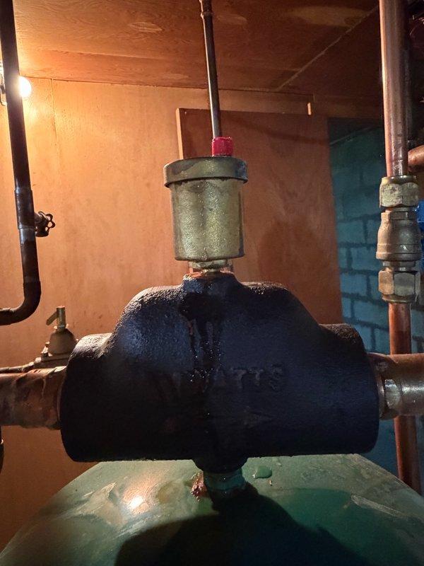 Responded to a water leak at the pressure valve assembly located above the pressure tank, which serves both the domestic water supply and boiler system. Upon inspection, identified a leaking Amtrol air vent (15 PSI rated) on the boiler system with visible moisture damage and oxidation on the surrounding components. Confirmed the leak was active and provided an estimate for replacement of the defective Amtrol air vent part to resolve the issue.