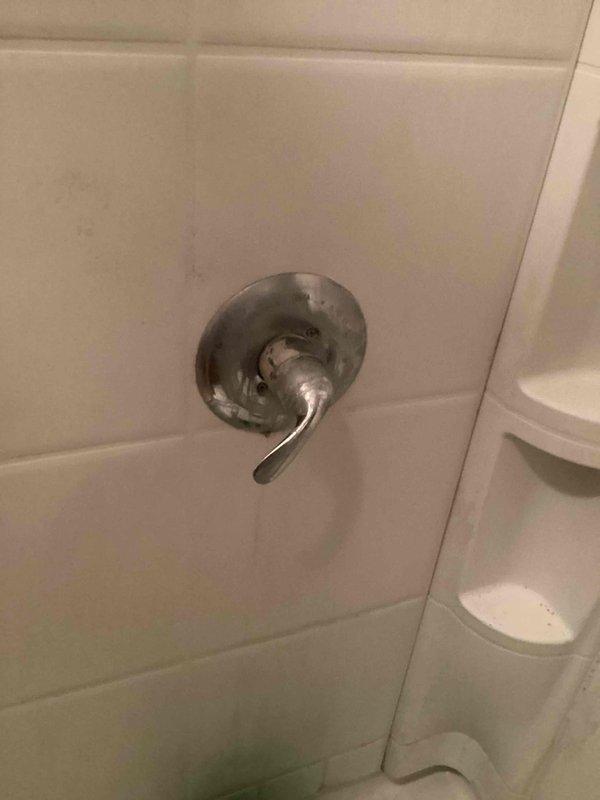 Responded to service call for multiple shower valve leaks in two bathrooms. Main bathroom shower exhibited water flow issues with improper distribution through the shower head during operation. Downstairs bathroom presented a faulty shower valve with continuous dripping and a broken control handle, showing significant discoloration and water staining on the escutcheon plate. Diagnosed failed internal valve components causing the persistent leak. Replaced defective shower valve assembly to restore proper water control and eliminate dripping condition.