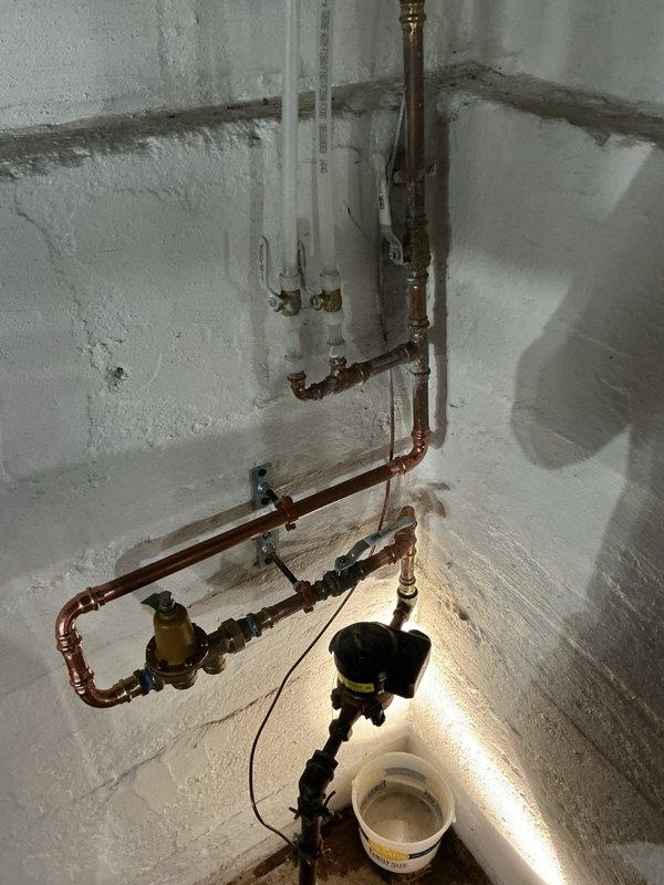 Responded to excessive water pressure issue measuring 110 psi at the main water supply line. Installed a three-quarter inch brass pressure reducing valve with isolation valves on the incoming copper water line to protect plumbing fixtures and appliances from potential damage. Mounted the PRV assembly to the basement wall using proper support brackets and configured the regulator to deliver a safe operating pressure of 70 psi. Tested system operation and verified consistent pressure output at the reduced setting.