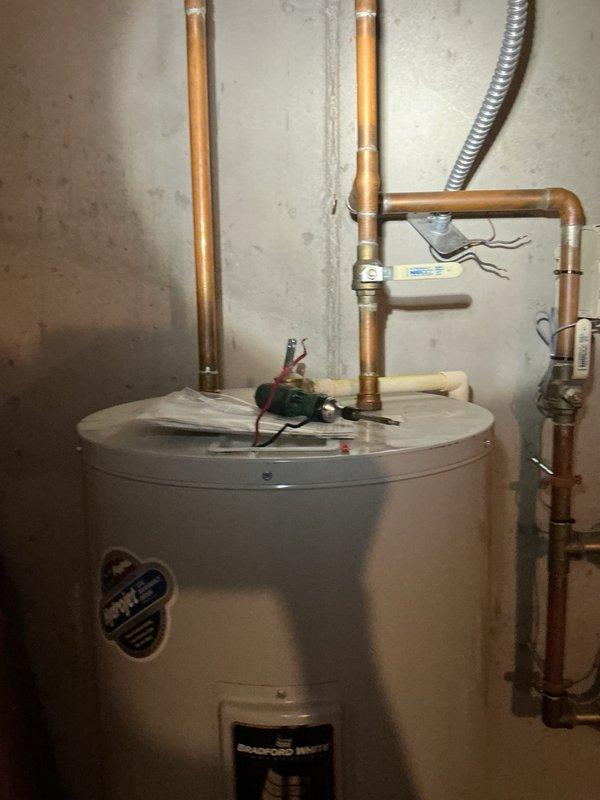 Responded to no hot water complaint and found tripped breaker with active leak from bottom of existing water heater tank. Removed and disposed of failed unit. Installed new 50-gallon electric Bradford White water heater with proper copper piping connections, dielectric unions, temperature and pressure relief valve, and electrical wiring to code. Tested system operation, verified no leaks, restored hot water service, and confirmed proper breaker function.