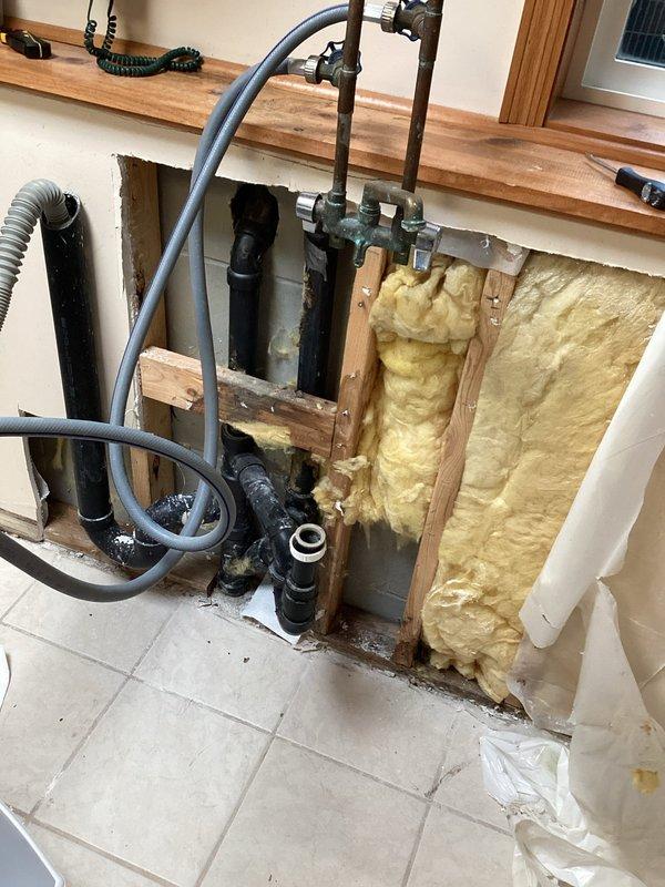 Completed comprehensive plumbing inspection at new commercial location, evaluating exposed wall cavity plumbing system including black PVC drain lines, copper supply piping, and associated fittings and connections. Inspected water treatment system including water softener unit with proper electrical connection and copper supply line routing in utility area. All plumbing systems photographed and documented for compliance verification.