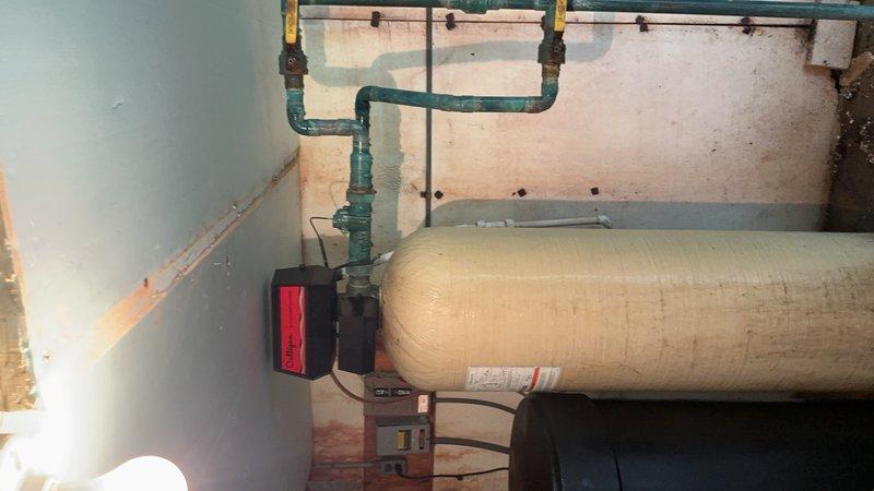 Responded to service call for leaking water softener system in pump house. Upon inspection, identified brine tank overfilling issue on commercial Culligan water softener unit causing water leakage in well house area. Documented equipment condition and malfunction with photographs showing water treatment system components including pressure tank, filtration vessels, and softener unit with visible moisture staining on concrete floor. Determined repair requires manufacturer-specific service and left voicemail advising property owner to contact Culligan directly for warranty service and specialized repair of brine tank overflow mechanism.