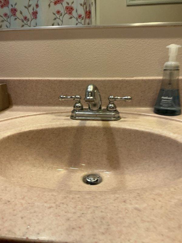 Responded to multiple plumbing issues throughout the residence involving kitchen and bathroom fixtures. Addressed leak underneath kitchen sink caused by deteriorated continuous waste piping; removed and replaced corroded metal drain assembly with reconfigured piping to ensure proper drainage and eliminate leak. Resolved low cold water pressure issue at bathroom faucet by removing and cleaning stem assembly, restoring adequate flow. Installed replacement pop-up drain assembly in bathroom vanity where previous mechanism was missing. Assessed toilet with inefficient flushing performance; replacement deferred pending homeowner decision. All completed repairs tested and verified operational.