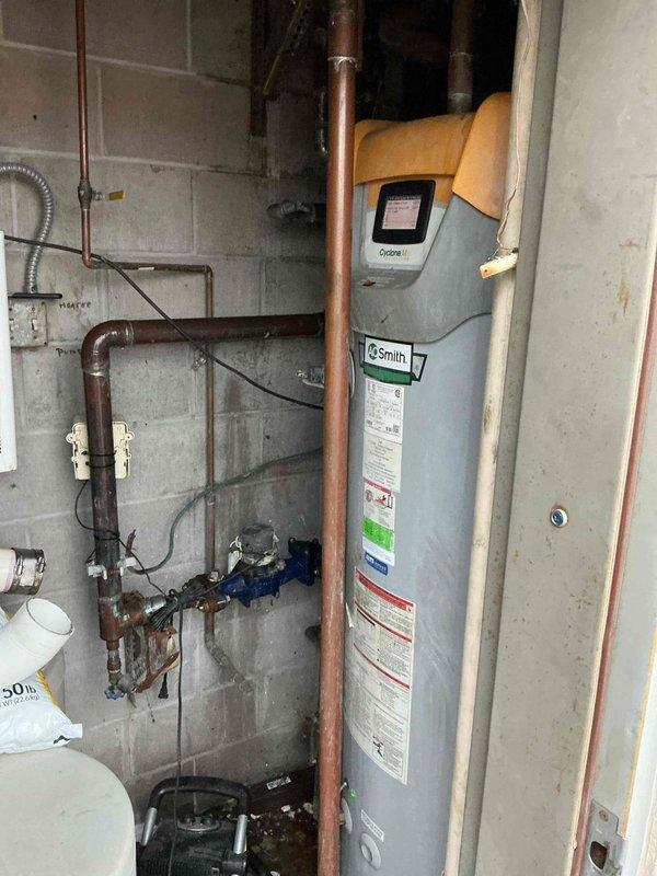 Responded to no hot water condition on commercial tankless water heater. Found intake blocked error code caused by condensate backup in exhaust system. Discovered exhaust drain pipe completely obstructed with approximately 6 inches of standing water due to severe internal corrosion and rust accumulation. Cleared blockage from condensate drain line, removed accumulated water, and reassembled exhaust components. Verified proper drainage function and restored unit to operational status.