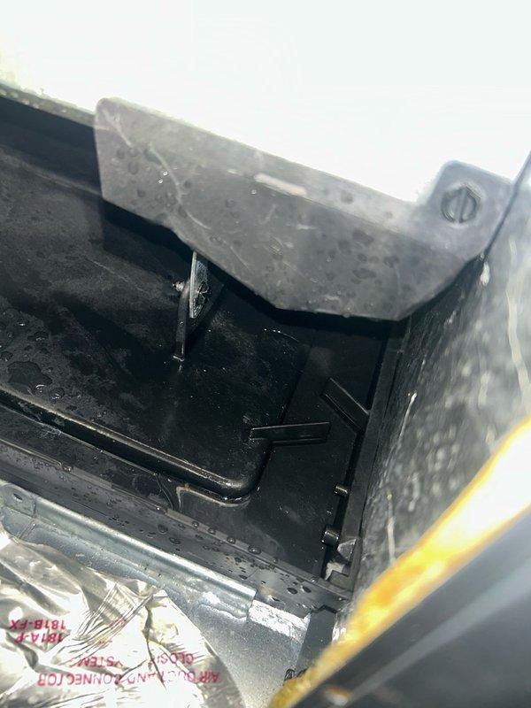 Responded to no-cool condition on recently installed AC system with water accumulation in secondary drain pan. Discovered water streaks on blower motor housing but found evaporator pan intact with no cracks and primary drain line functioning properly. Removed standing water from secondary pan using vacuum, cleaned and dried flood switch, repositioned float switch for proper water detection. System requires follow-up appointment to identify source of water intrusion as leak origin remains undetermined.