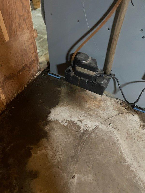 Responded to no cooling complaint with water leaking on floor. Found tripped outlet supplying power to condensate pump, causing system shutdown and water overflow onto concrete floor. Reset circuit breaker and restored power to pump, which resumed normal condensation removal operation. Inspected unit and noted rust staining and water streaks on equipment and surrounding area from previous overflow. Verified Rheem furnace returned to normal operation, checked air filters, and confirmed condensate drain system functioning properly with pump actively removing water from drain pan.