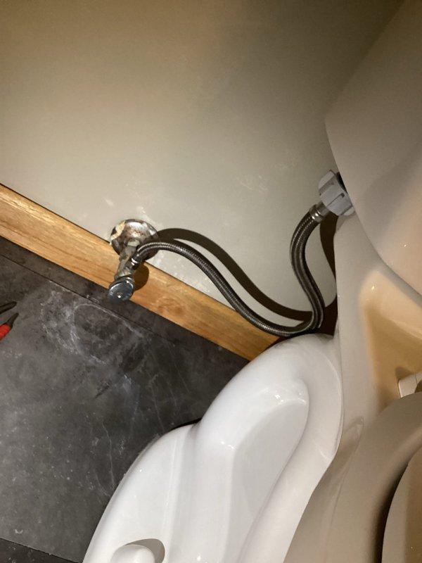 Responded to a toilet leak reported at the base of the fixture. Upon inspection, determined the leak was originating from a faulty flexible braided stainless steel supply line rather than the wax ring seal. The water supply to the toilet had been shut off prior to arrival. Replaced the defective supply line with a new braided stainless steel flex line, secured all connections at both the shut-off valve and toilet tank fill valve, restored water supply, and tested the system to confirm proper operation with no leaks present.