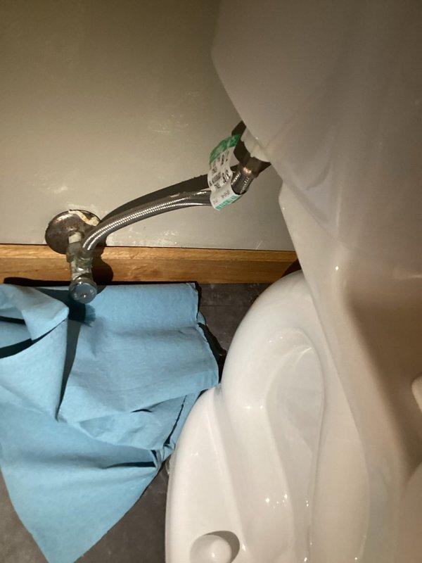 Responded to a toilet leak reported at the base of the fixture. Upon inspection, determined the leak was originating from a faulty flexible braided stainless steel supply line rather than the wax ring seal. The water supply to the toilet had been shut off prior to arrival. Replaced the defective supply line with a new braided stainless steel flex line, secured all connections at both the shut-off valve and toilet tank fill valve, restored water supply, and tested the system to confirm proper operation with no leaks present.