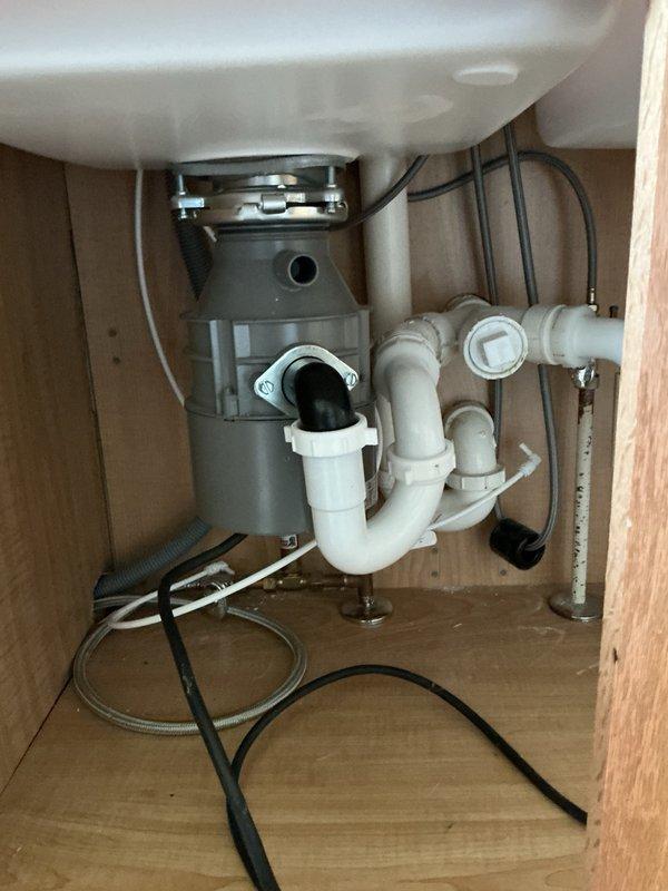 Completed kitchen plumbing reconnection following new countertop installation, including installation of new kitchen faucet, reconnection of undermount sink, and re-installation of existing garbage disposal unit. During garbage disposal hookup, encountered clearance issue where disposal unit sat too low for proper drain alignment. Applied slight back pitch to drain line to achieve proper connection with existing P-trap configuration. Advised customer of alternative solution to lower drain assembly by modifying P-trap connection if future adjustment becomes necessary. All water supply lines reconnected and tested for proper operation. Verified garbage disposal electrical connection and functionality upon completion.