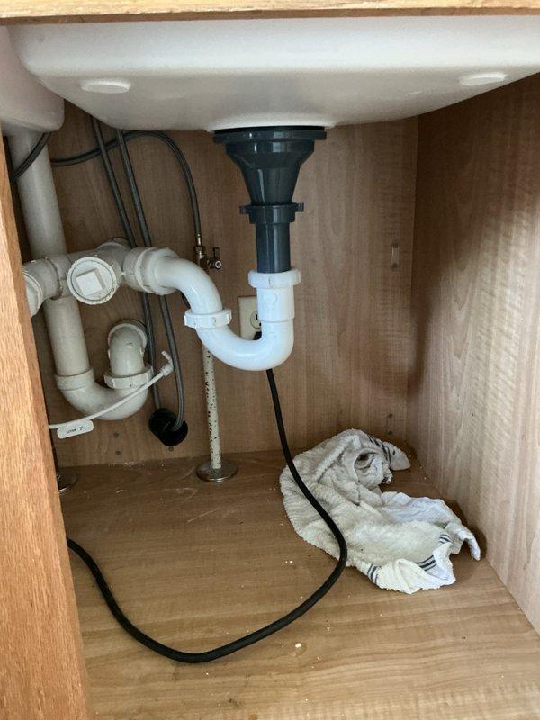 Completed kitchen plumbing reconnection following new countertop installation, including installation of new kitchen faucet, reconnection of undermount sink, and re-installation of existing garbage disposal unit. During garbage disposal hookup, encountered clearance issue where disposal unit sat too low for proper drain alignment. Applied slight back pitch to drain line to achieve proper connection with existing P-trap configuration. Advised customer of alternative solution to lower drain assembly by modifying P-trap connection if future adjustment becomes necessary. All water supply lines reconnected and tested for proper operation. Verified garbage disposal electrical connection and functionality upon completion.