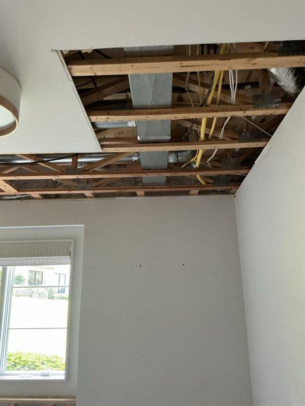 Responded to follow-up service call to investigate water leak affecting ceiling near washing machine location. Ceiling drywall had been previously removed to access plumbing infrastructure above subfloor level. Conducted thorough inspection of exposed joists, ductwork, and plumbing lines in ceiling cavity to locate source of leak. Ran washing machine through complete cycle while monitoring supply lines, drain connections, and surrounding plumbing components for active water discharge. Inspected flexible braided supply hoses, shut-off valves, and drain connections at washer location. Traced leak path from subfloor area through ceiling structure to determine origin point of water intrusion. Documented findings with photographic evidence showing exposed ceiling framework, mechanical systems, and affected areas for repair recommendations.