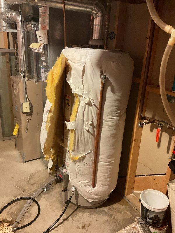 Responded to service call for leaking water heater in residential basement. Upon arrival, assessed 1993 vintage tanked water heater showing signs of active water leak. Conducted thorough inspection of unit, surrounding plumbing connections, and copper supply lines to identify leak source and evaluate overall condition of aging equipment. Documented existing insulation wrap and configuration of water heater installation adjacent to furnace system. Due to age of unit (30+ years) and active leak condition, provided customer with replacement options and estimates for new water heater installation. Explained risks of continued operation with current leaking unit and recommended prompt replacement to prevent water damage and ensure reliable hot water service.