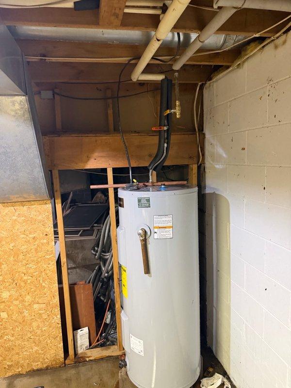 Responded to water heater leak originating from top connections. Upon inspection, identified pinhole leak in flexible copper supply line and additional leak at tee fitting on main water line. Replaced failed flexible water heater supply line with new connector and installed new tee fitting on main water line to eliminate both leak sources. System tested and verified operational with no active leaks upon completion.