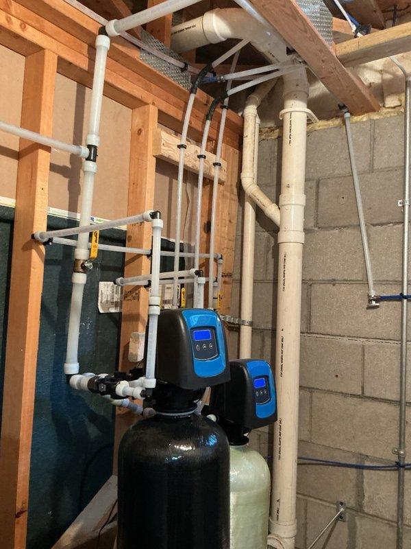 Completed annual plumbing inspection in response to reported low water pressure issues. Conducted thorough examination of bathroom fixtures including tub/shower valve assembly and spout with diverter mechanism, as well as basement water treatment system consisting of dual water softener/filtration units with digital controls and associated PVC supply and distribution plumbing. All fixtures and equipment photographed and documented for service records.